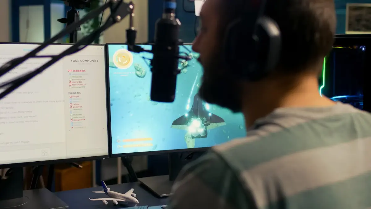 A person with headphones sits in front of dual monitors displaying an underwater gaming scene, alongside a model airplane.