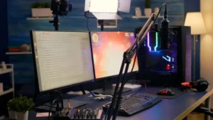 A modern streaming setup featuring dual monitors, a microphone, gaming headset, and colorful PC, all in a well-lit room.
