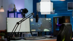 A modern gaming setup featuring dual monitors, a microphone, camera, and colorful PC, illuminated by soft studio lighting.