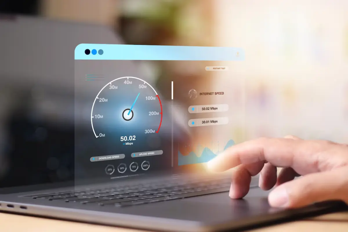 A finger hovers over a laptop touchpad displaying an internet speed test with results of 50.02 Mbps download and 30.01 Mbps upload.
