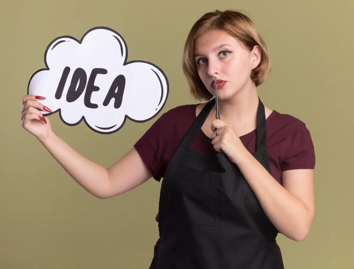 A person in an apron holds a large speech bubble sign reading 