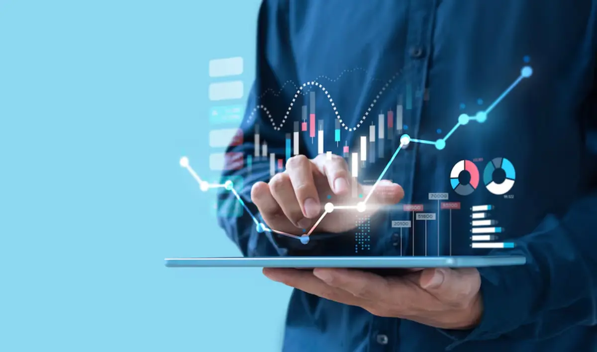 A user interacts with a tablet displaying vibrant, digital financial graphs and data visualizations against a blue background.