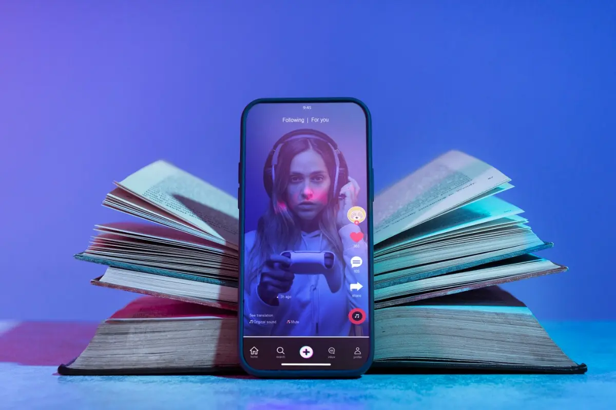 A smartphone displaying a social media app is positioned on an open book, set against a gradient blue background.