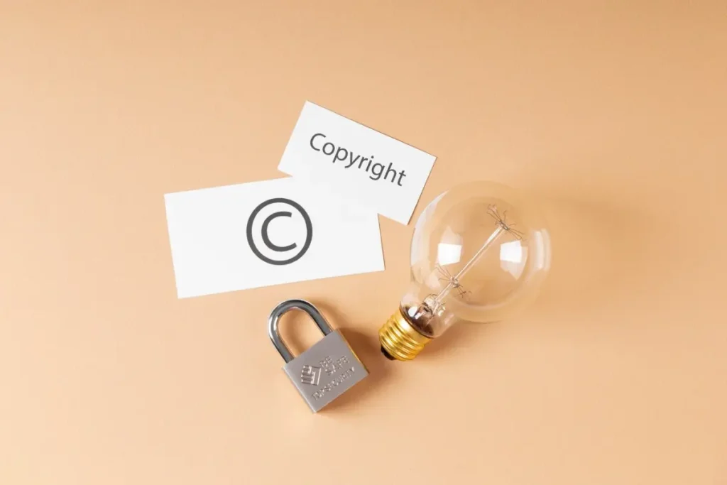 A light bulb, lock, and two cards marked Copyright and © on a beige background, symbolizing intellectual property protection.